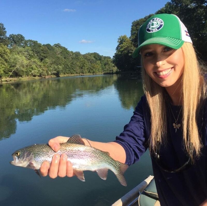Jennifer Sullivan fly fishing on an Arkansas river, holding a brown trout